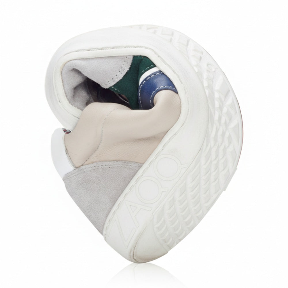 Der QLAUDE Grey Sneaker von ZAQQ, ein Herren-Barfußschuh, der in den Farbtönen Grau, Beige, Weiß und Grün erhältlich ist, wird gedreht präsentiert, um seine Flexibilität hervorzuheben. Das Wort „ZOO“ ist auf der ZAQQ-Sohle sichtbar, die ein strukturiertes Muster aufweist.